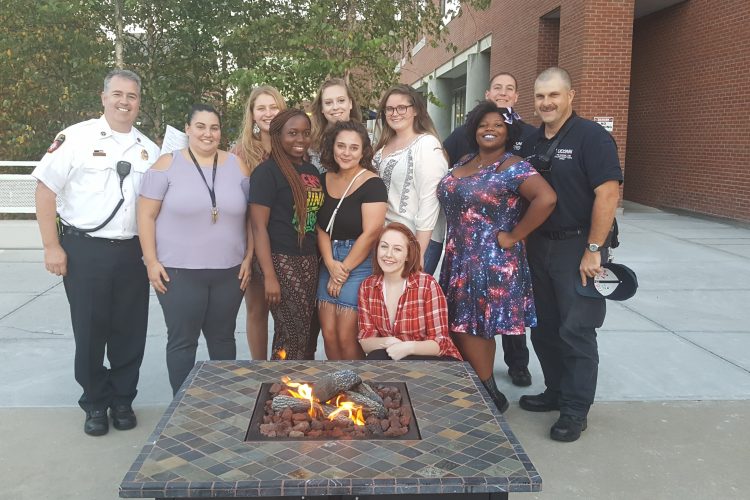 Group of participants gathered around fireplace and smiling for a picture